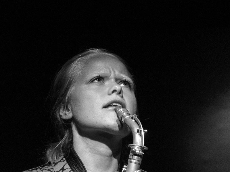 Sort-hvitt-foto av Mette Rasmussen som synger i en mikrofon.