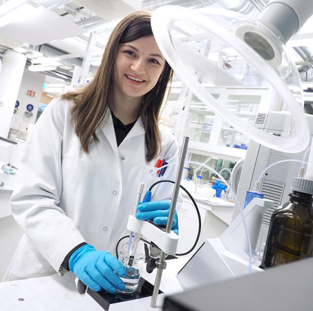 A picture of a woman working in a lab with a white lab coat.