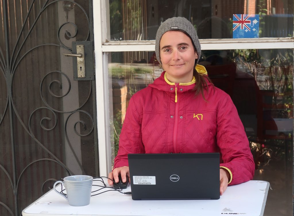 A picture of a woman working outside with a laptop.