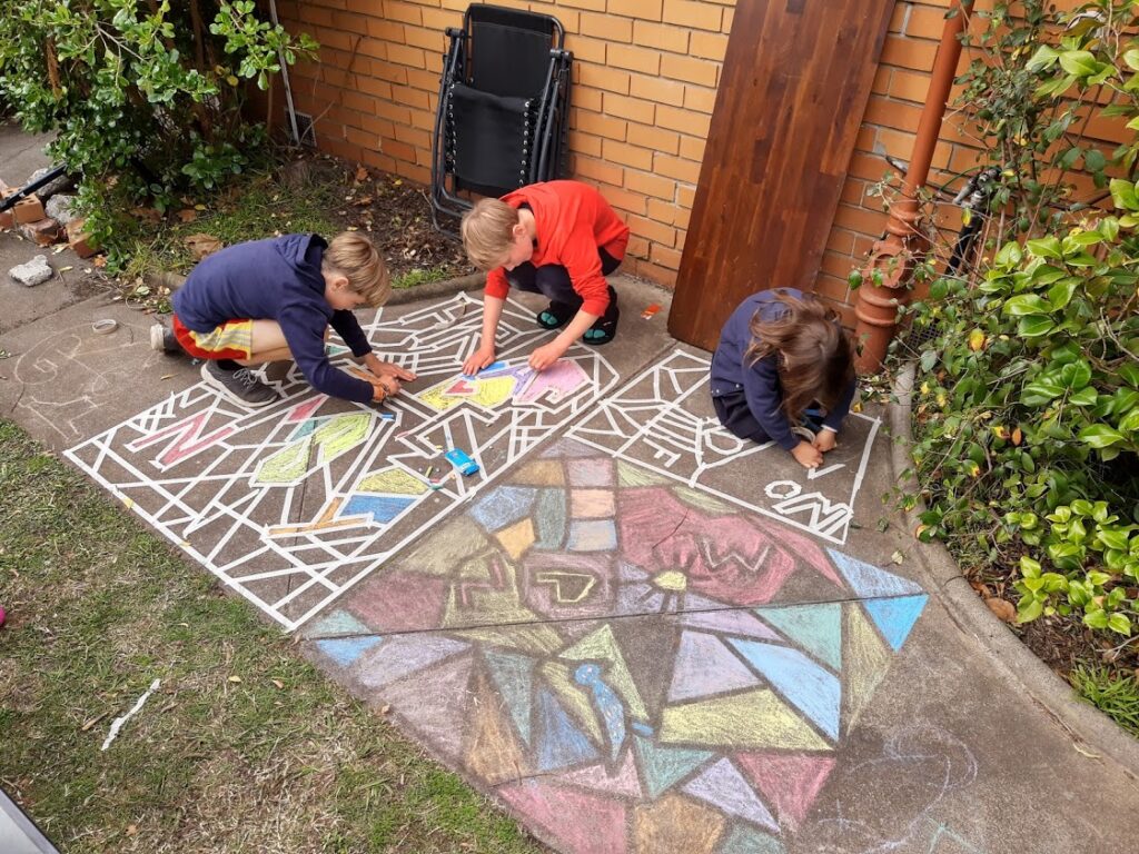 A picture of three children creating colorful street art.
