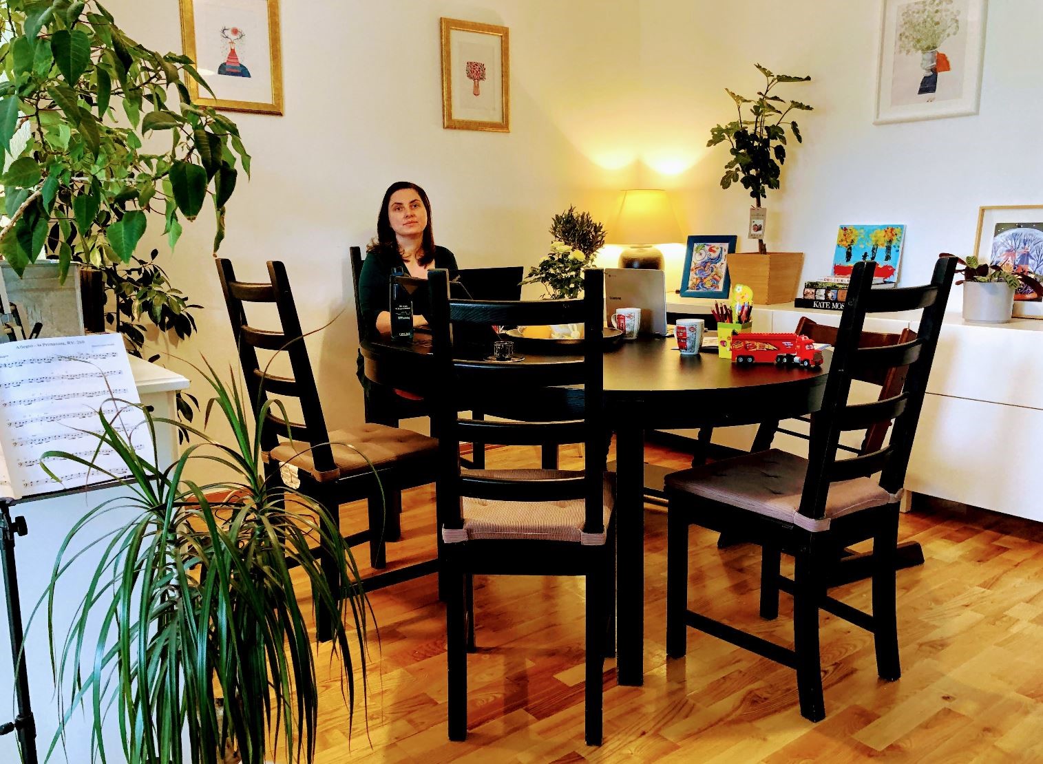 A picture of a woman sitting in her home office, which is a kithen table.