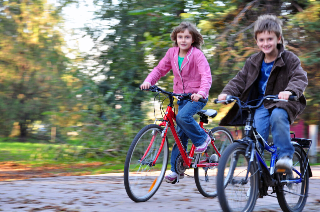 Et bilde av to barn som sykler utendørs.