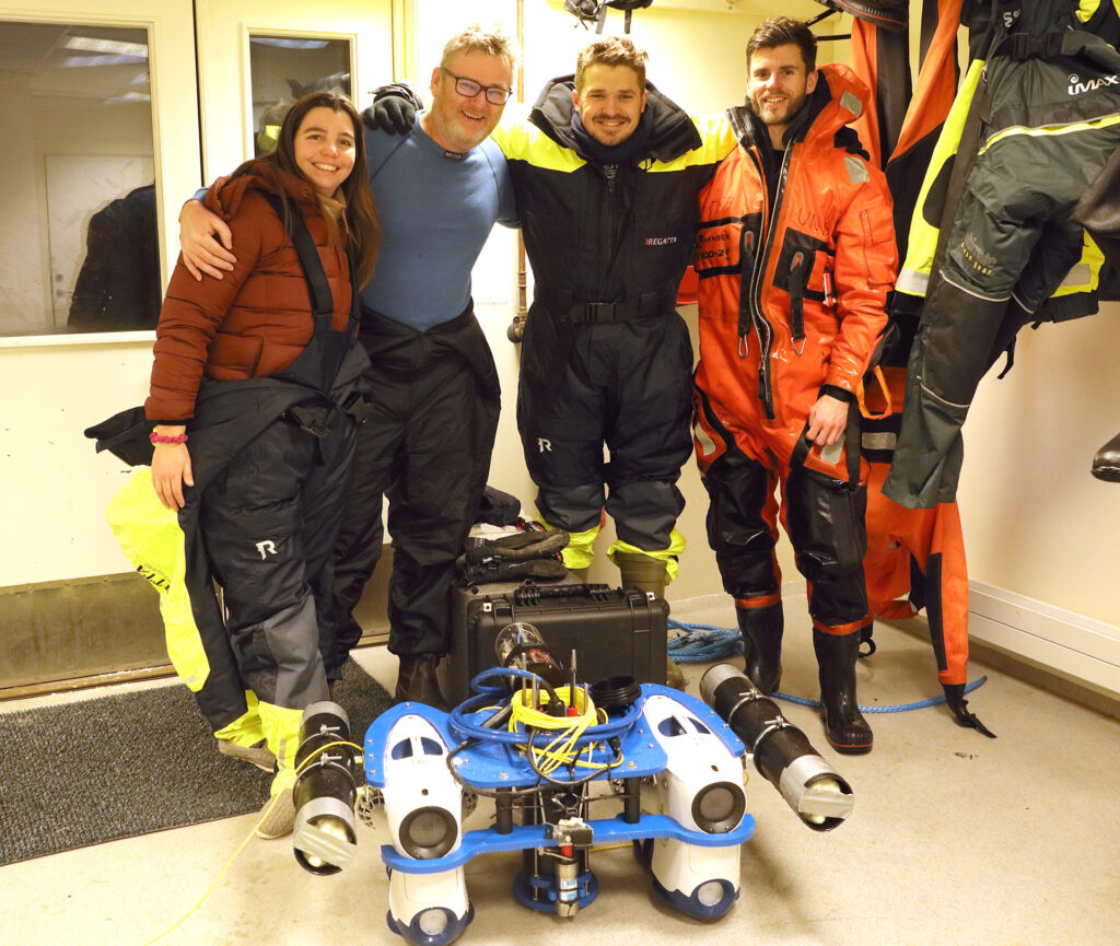 A photo of four people in front of a ROV.