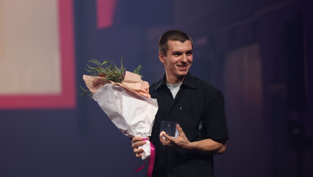 En mann holder en blomsterbukett og smiler