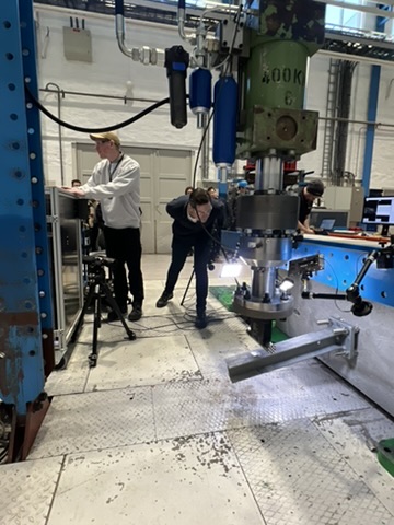 Bildet viser en mann som sjekker et stålprofil etter en test i mekanisk lab. Bilde til artikkel om test av rekkverk på bruer.